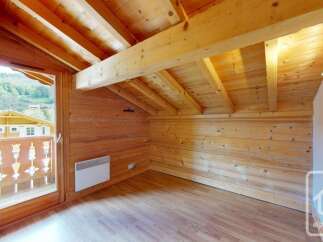 Experience rustic charm in this attic room, featuring exposed wooden beams and paneling that create a warm, inviting atmosphere.