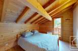 Experience rustic charm in this cozy bedroom, featuring warm wooden walls and a vaulted ceiling with exposed beams.