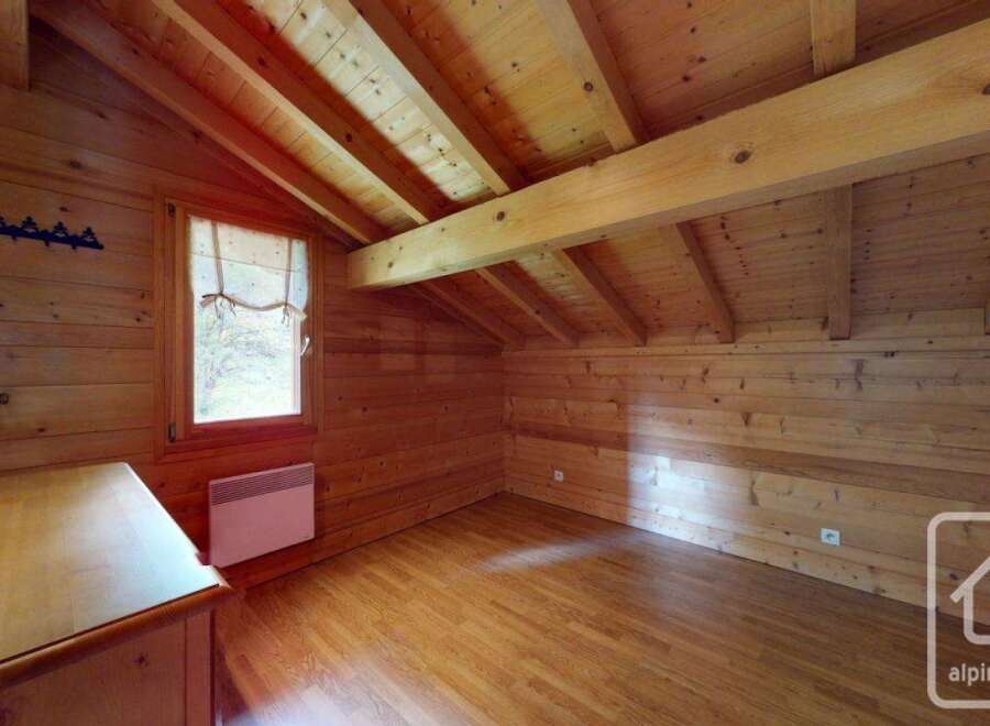 Experience cozy living in this charming wooden attic room, featuring exposed beams and a warm, natural wood finish throughout.