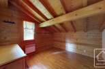 Experience cozy living in this charming wooden attic room, featuring exposed beams and a warm, natural wood finish throughout.