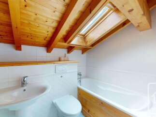 This charming bathroom features a vaulted wooden ceiling with exposed beams and a skylight, bathing the space in natural light.