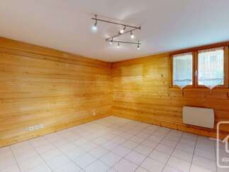 Experience cozy living in this charming room featuring warm, wood-paneled walls and a bright, tiled floor.