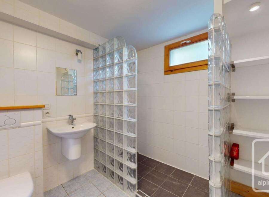 This bathroom features a modern design with white tiled walls and a glass block shower enclosure.