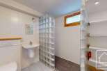 This bathroom features a modern design with white tiled walls and a glass block shower enclosure.