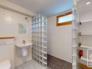 This bathroom features a modern design with white tiled walls and a glass block shower enclosure.