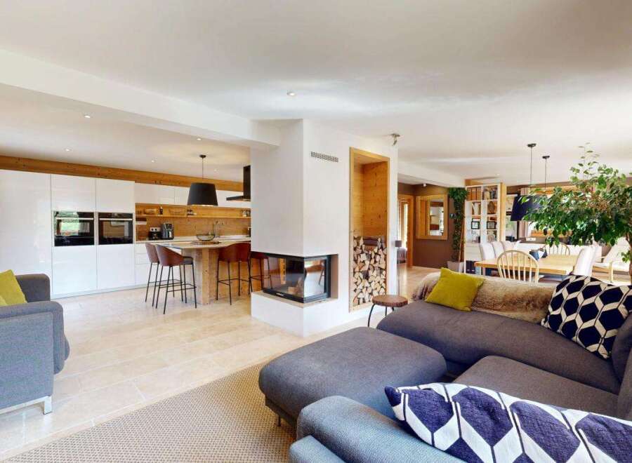 Experience modern living in this open-concept home, featuring a sleek white kitchen with integrated appliances and a stylish island with bar seating.