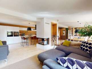 Experience modern living in this open-concept home, featuring a sleek white kitchen with integrated appliances and a stylish island with bar seating.