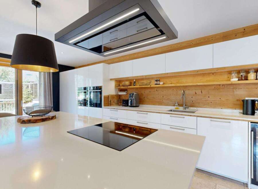 Experience modern luxury in this stunning kitchen, featuring sleek white cabinetry and a warm wooden accent wall.