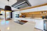 Experience modern luxury in this stunning kitchen, featuring sleek white cabinetry and a warm wooden accent wall.