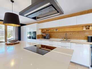 Experience modern luxury in this stunning kitchen, featuring sleek white cabinetry and a warm wooden accent wall.