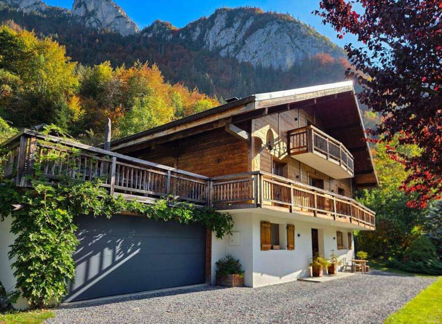 Experience the charm of this stunning wooden chalet nestled against a backdrop of majestic mountains and vibrant autumn foliage.