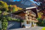 Experience the charm of this stunning wooden chalet nestled against a backdrop of majestic mountains and vibrant autumn foliage.