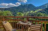 Enjoy breathtaking mountain views from this charming balcony, complete with a cozy seating area and a small table.