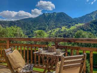 Enjoy breathtaking mountain views from this charming balcony, complete with a cozy seating area and a small table.