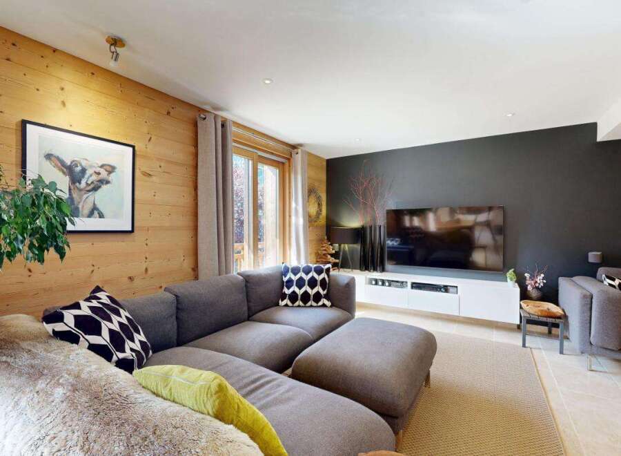 Experience cozy living in this charming living room, featuring warm wood-paneled walls and a comfortable sectional sofa.