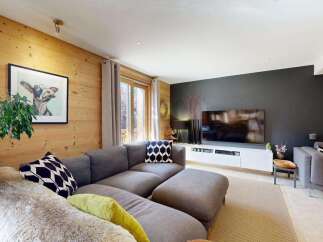 Experience cozy living in this charming living room, featuring warm wood-paneled walls and a comfortable sectional sofa.