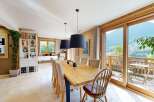 Experience breathtaking mountain views from this elegant dining room, featuring a large wooden table perfect for family gatherings.