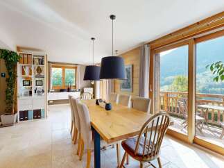 Experience breathtaking mountain views from this elegant dining room, featuring a large wooden table perfect for family gatherings.