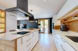 Experience modern luxury in this stunning kitchen, featuring a sleek island with a built-in stovetop and a sophisticated overhead extractor fan.