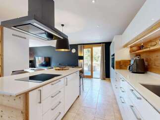 Experience modern luxury in this stunning kitchen, featuring a sleek island with a built-in stovetop and a sophisticated overhead extractor fan.