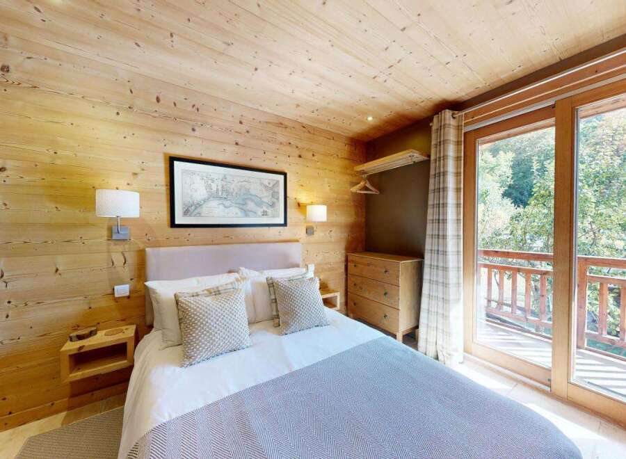 Experience cozy mountain living in this charming bedroom, featuring warm wooden walls and a comfortable bed adorned with plush pillows.