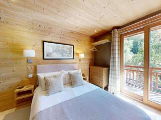 Experience cozy mountain living in this charming bedroom, featuring warm wooden walls and a comfortable bed adorned with plush pillows.