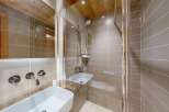 Experience modern luxury in this beautifully appointed bathroom, featuring a sleek white vessel sink with chrome wall-mounted faucets and a spacious walk-in shower with a rainfall showerhead.