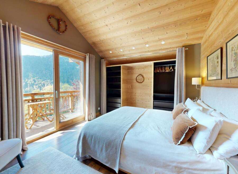 Experience breathtaking mountain views from this charming bedroom, featuring a spacious king-size bed with plush linens and a cozy armchair.