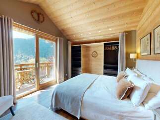 Experience breathtaking mountain views from this charming bedroom, featuring a spacious king-size bed with plush linens and a cozy armchair.