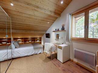 Experience cozy living in this charming bedroom featuring a comfortable bed, built-in shelving, and a dedicated workspace.