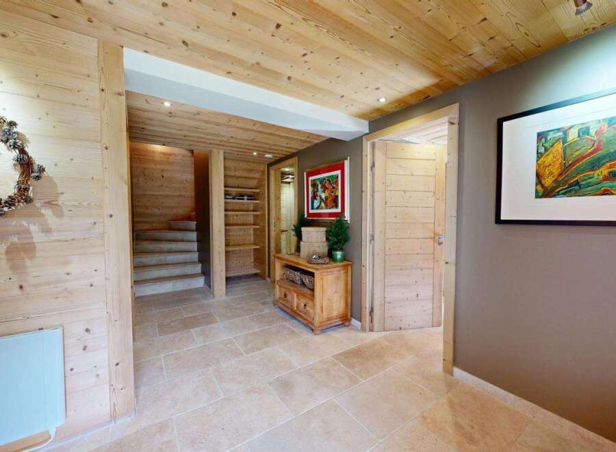 Step into a warm and inviting entryway featuring natural wood paneling and a charming pinecone wreath.