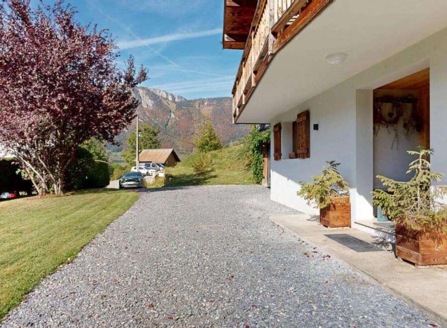 Experience the charm of this alpine property, featuring a welcoming entrance with rustic wooden shutters and planters.