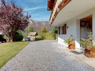 Experience the charm of this alpine property, featuring a welcoming entrance with rustic wooden shutters and planters.
