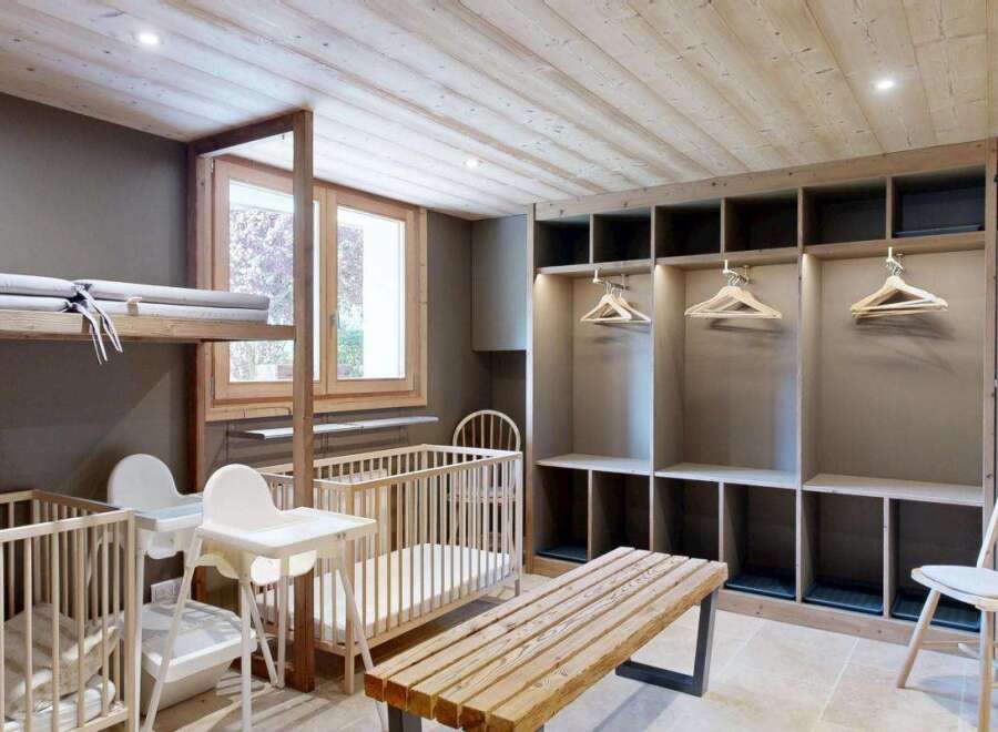 This charming nursery room features two wooden cribs, each equipped with a comfortable mattress and a pillow.