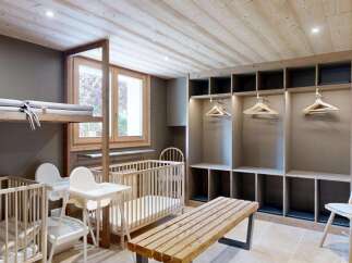 This charming nursery room features two wooden cribs, each equipped with a comfortable mattress and a pillow.