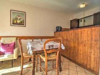 Enjoy a cozy dining experience in this charming space, featuring a rustic wooden table set with a patterned tablecloth and complemented by two classic wooden chairs.