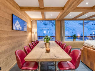 Experience luxury mountain living in this stunning dining area, featuring a long, rustic wooden table perfect for gathering with loved ones.