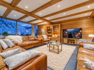 Experience luxury mountain living in this stunning living room, featuring plush leather sofas and a cozy, rustic ambiance.