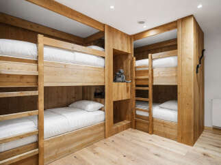 Experience cozy comfort in this charming bedroom featuring custom-built wooden bunk beds, perfect for families or groups.