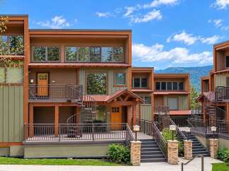 Discover modern mountain living in this stunning multi-level residence, featuring a striking blend of natural wood and earthy green siding.