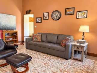 Step into a cozy living room featuring a comfortable gray sofa adorned with decorative pillows, perfect for relaxing evenings.