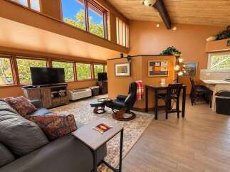 Experience comfortable living in this spacious room featuring a large gray sectional sofa with decorative pillows, a recliner with an ottoman, and a TV entertainment center.