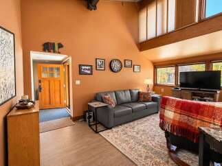 Step into this inviting living room featuring a cozy grey sofa adorned with decorative pillows, perfect for relaxing evenings.