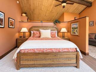 Experience rustic charm in this inviting bedroom, featuring a sturdy wooden bed frame and warm, orange-toned walls.