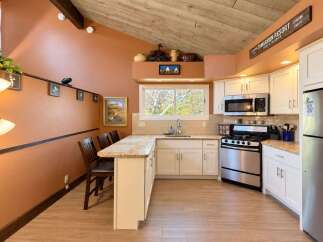 This charming kitchen boasts a vaulted wood-paneled ceiling and warm terracotta walls, creating a cozy and inviting atmosphere.