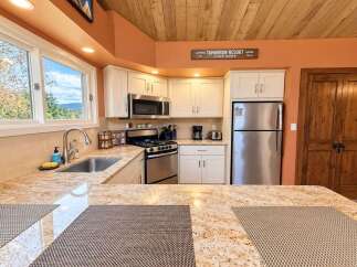 Experience the charm of this cozy kitchen, featuring sleek stainless steel appliances including a microwave, oven, and refrigerator.