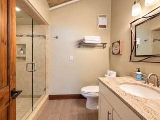 This beautifully appointed bathroom features a spacious glass-enclosed shower with elegant tile work and a convenient built-in niche for toiletries.