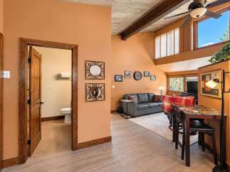 Step into this inviting living space featuring a vaulted ceiling with exposed wooden beams and a cozy seating area.