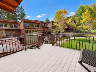 Enjoy the crisp autumn air from this spacious deck, offering stunning views of the surrounding trees with vibrant fall foliage.