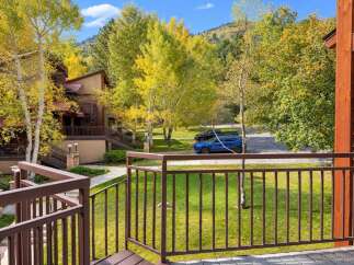 Experience the beauty of autumn from this property, surrounded by vibrant yellow aspen trees and lush green lawns.